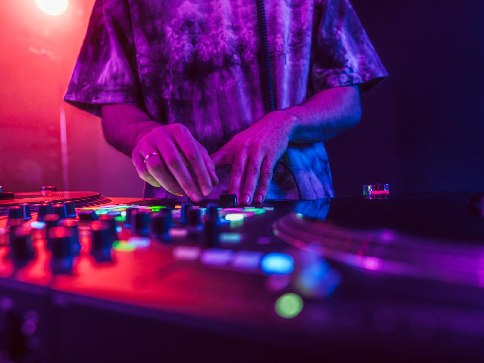 Close up of DJ hands on dj console mixer during concert in the night club